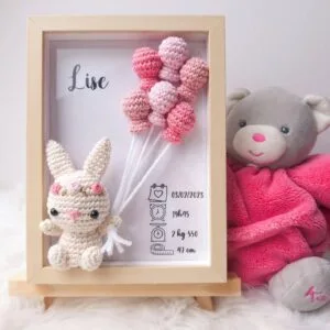 Cadre de naissance, fait main, avec un adorable lapin et sa couronne de fleurs en coton crocheté. Chaque section du cadre est personnalisée avec le prénom, la date et l'heure de naissance, le poids et la taille du bébé. Un souvenir et une décoration raffinée pour la chambre de bébé.